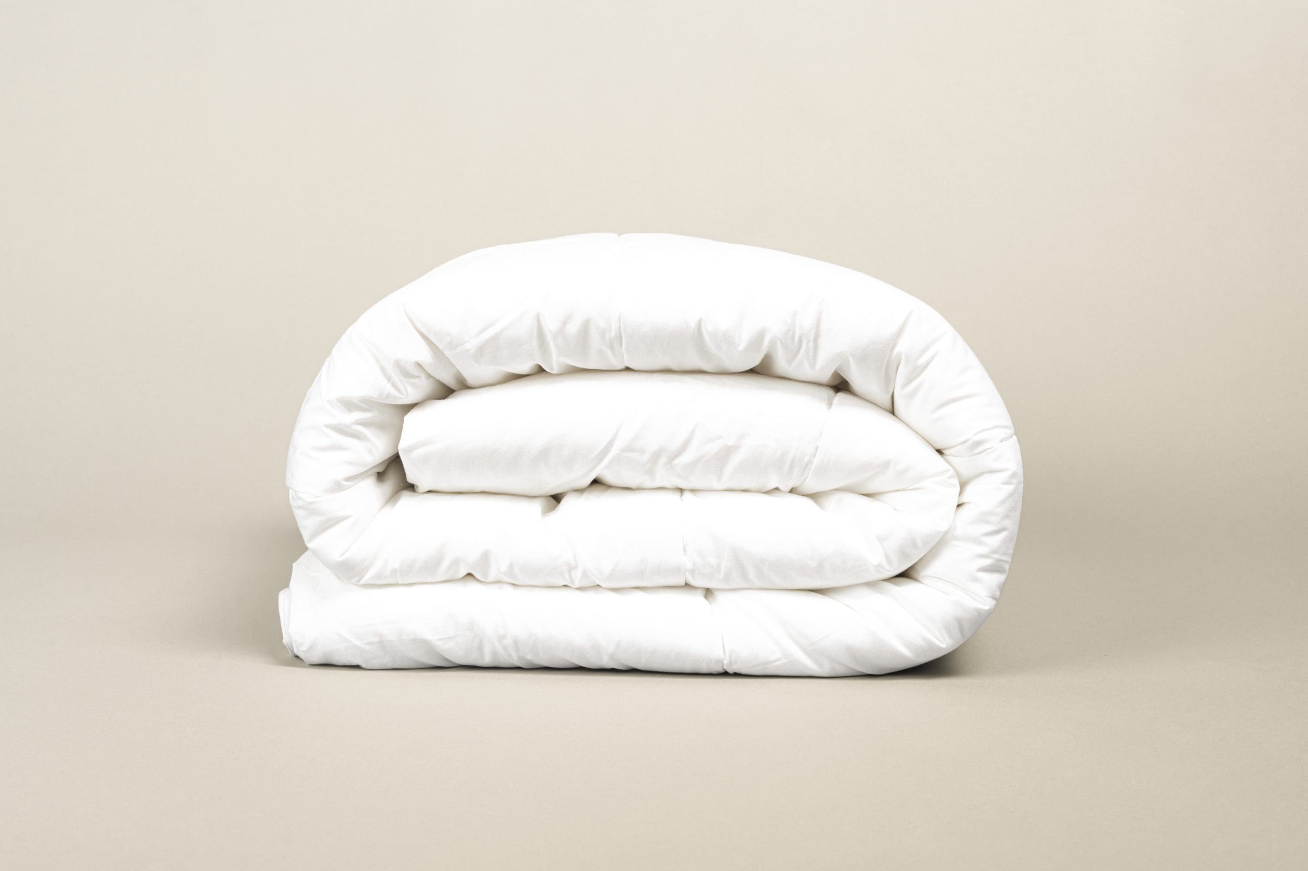 A neatly folded white comforter against a plain background.